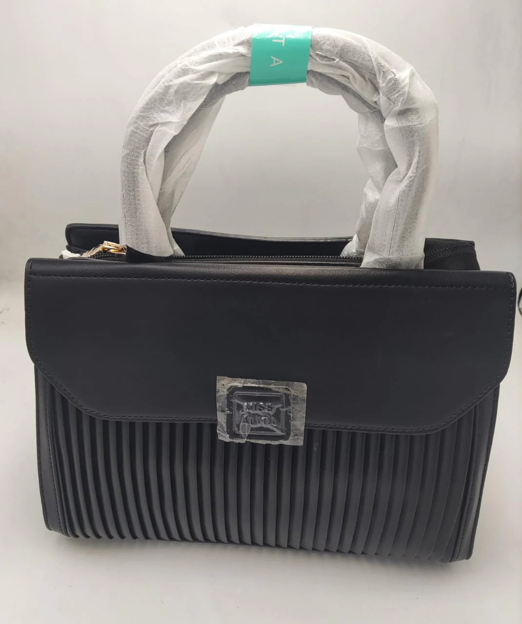 Black textured wave flap handbag with pleated design on a white background