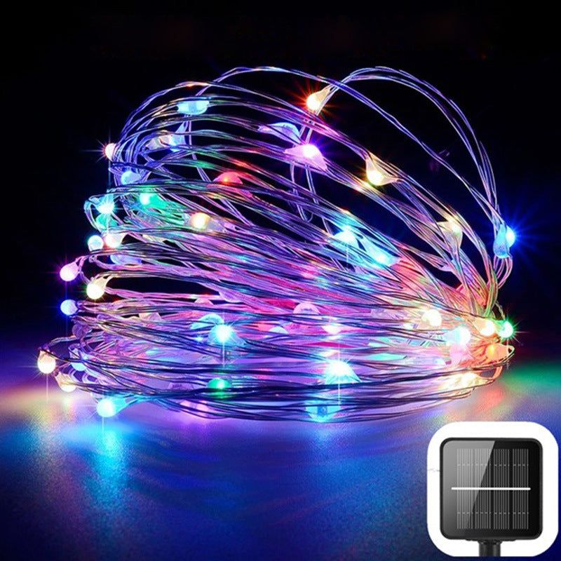 Multicolored string lights with a solar panel attachment on a dark background