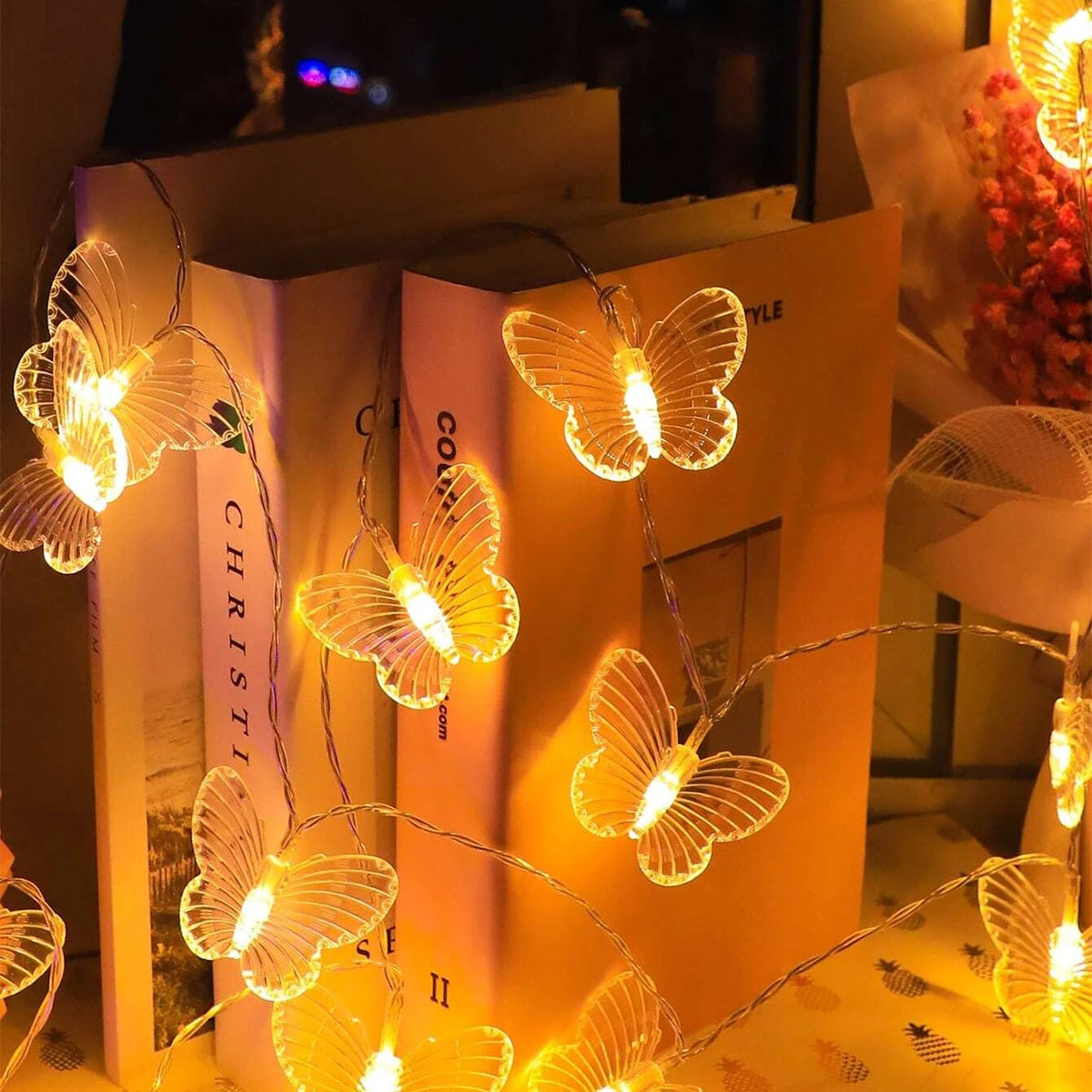 Butterfly-shaped string lights on a bookshelf with warm glow