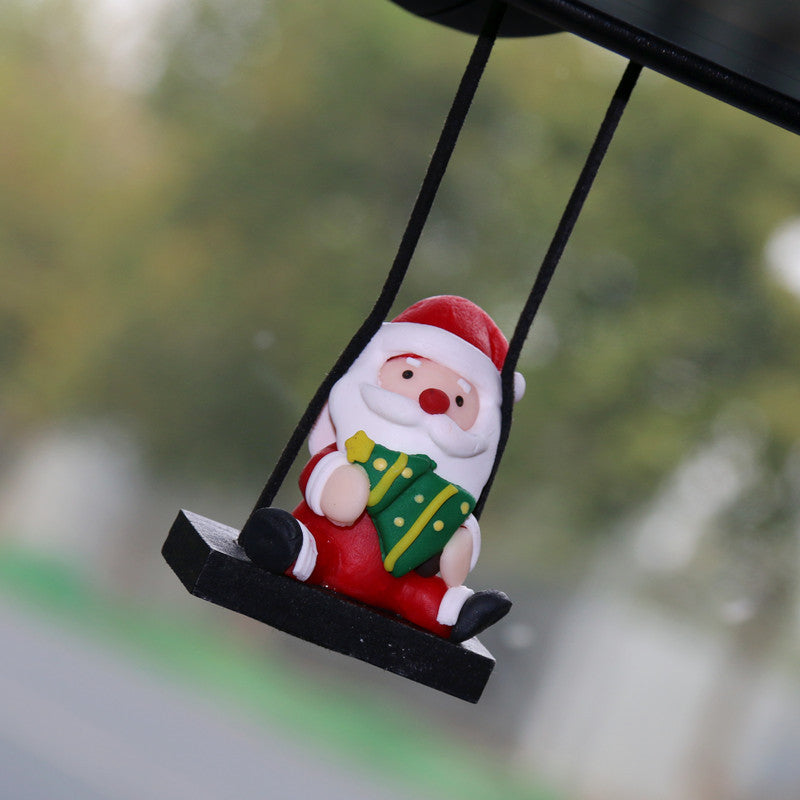 Christmas Car Rearview Mirror Pendant Santa Claus figurine on a swing with a blurred green background