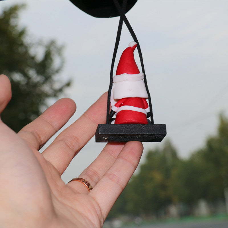 Hand holding a small Christmas Car Rearview Mirror Pendant with a black base against a blurred outdoor background