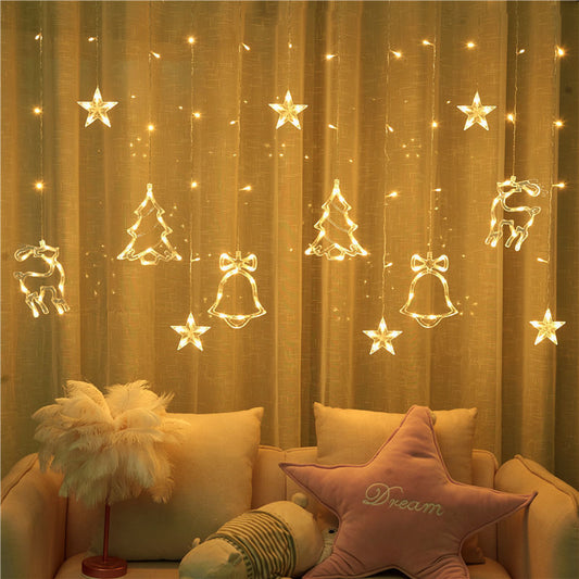 Decorative string lights with Christmas-themed decorations on a curtain, with a cozy living room setting.