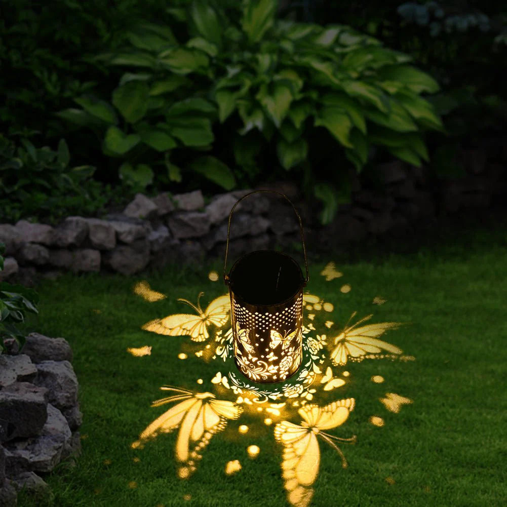 Outdoor Pluggable Or Hanging Iron Solar Butterfly Projector Lamp on grass at night