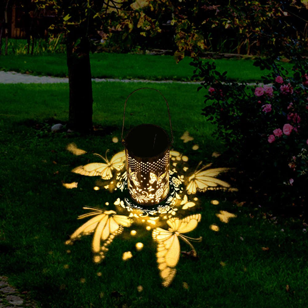 Outdoor Pluggable Or Hanging Iron Solar Butterfly Projector Lamp with butterfly projections on grass in a garden 