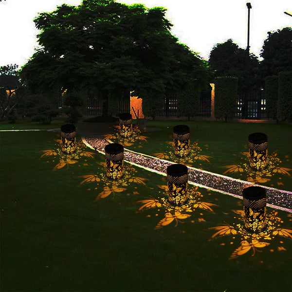 Outdoor Pluggable Or Hanging Iron Solar Butterfly Projector Lamp on a garden path casting floral patterns on the ground