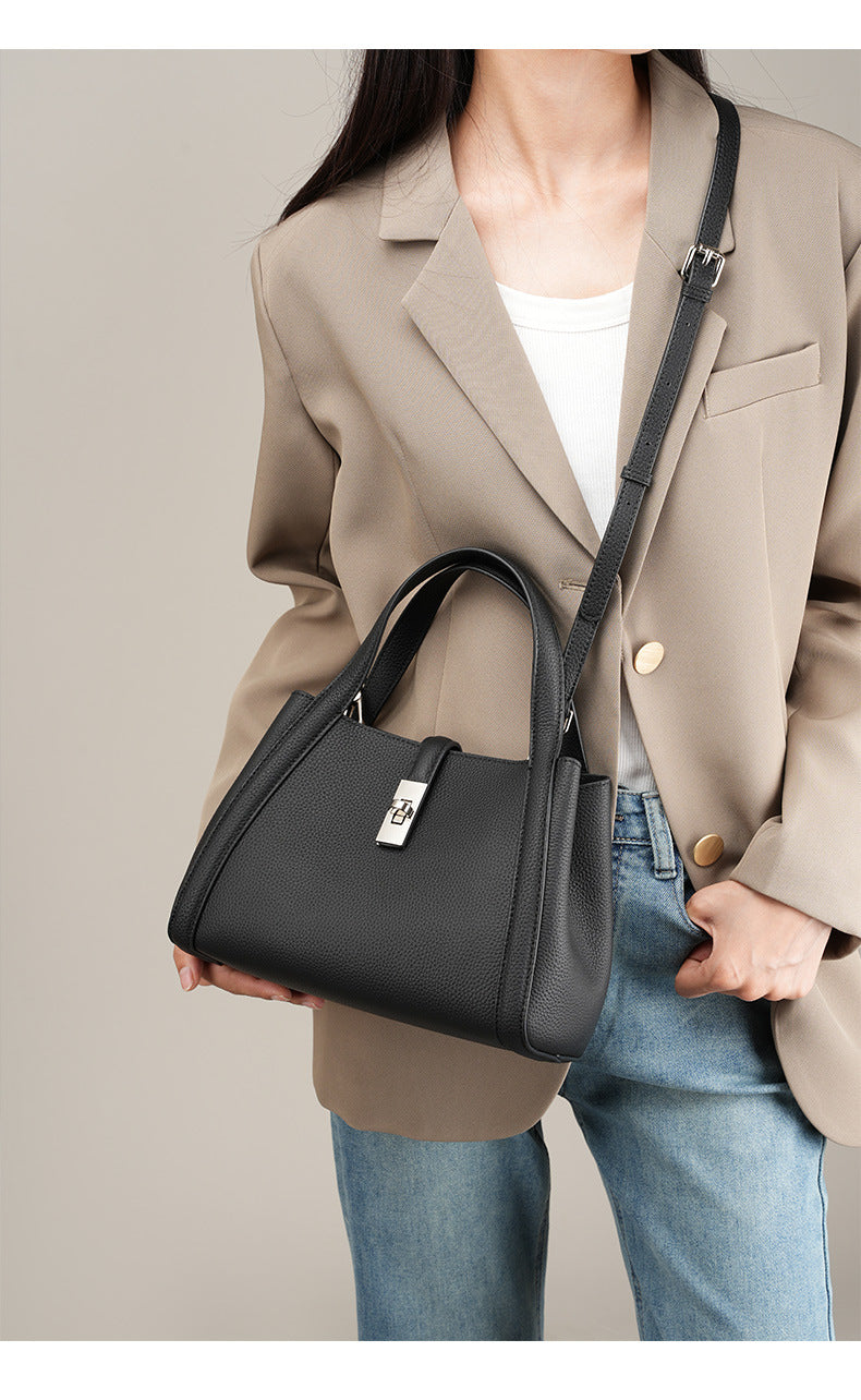 Person wearing a beige blazer and holding a black fashionable Korean style large capacity handbag against a neutral background 