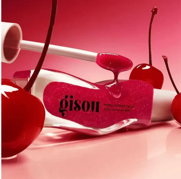 Gisou honey infused lip oil product with red cherry toppings on a pink background