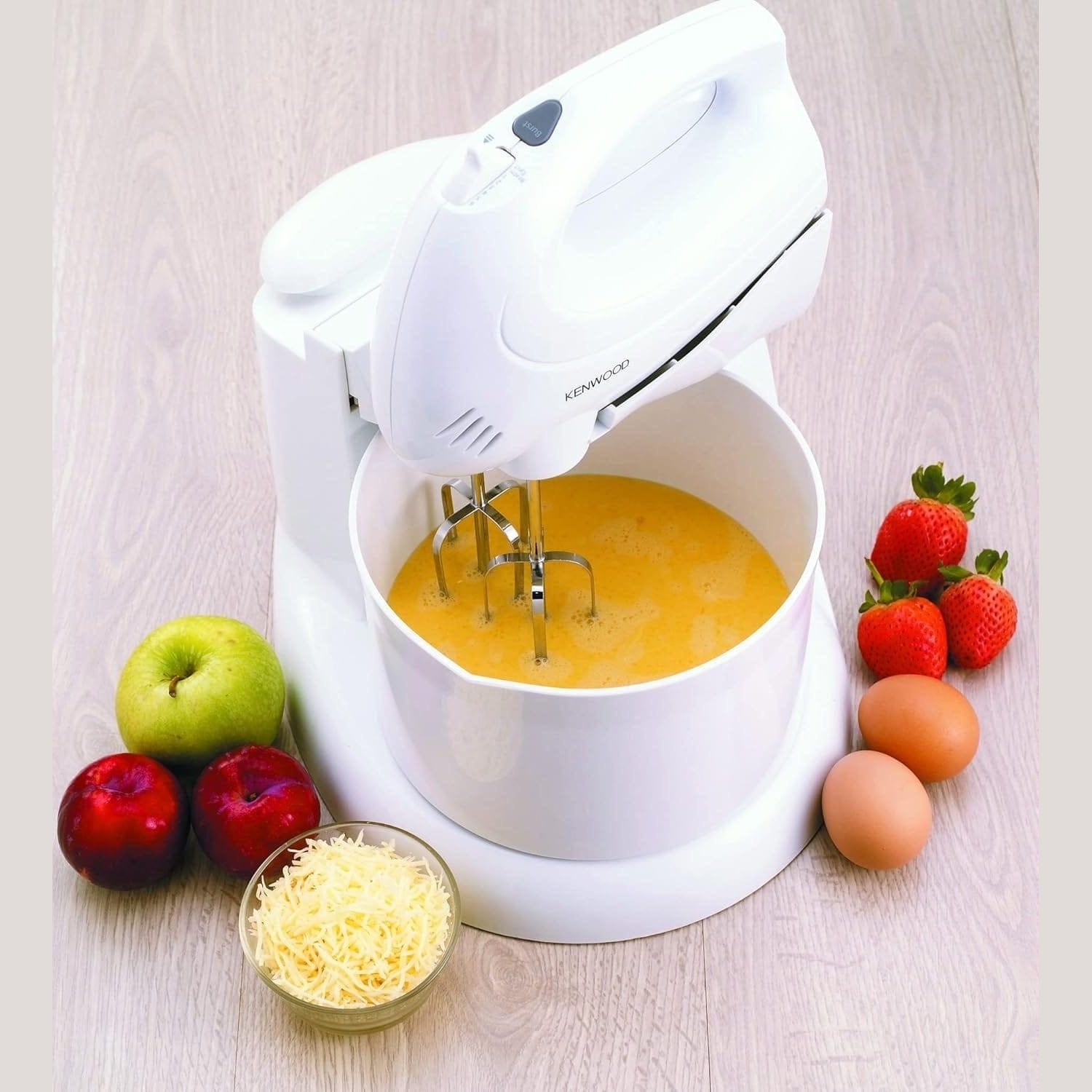 White Kenwood Hand Mixer with Bowl (HM430) with eggs and fruits on a light wooden surface