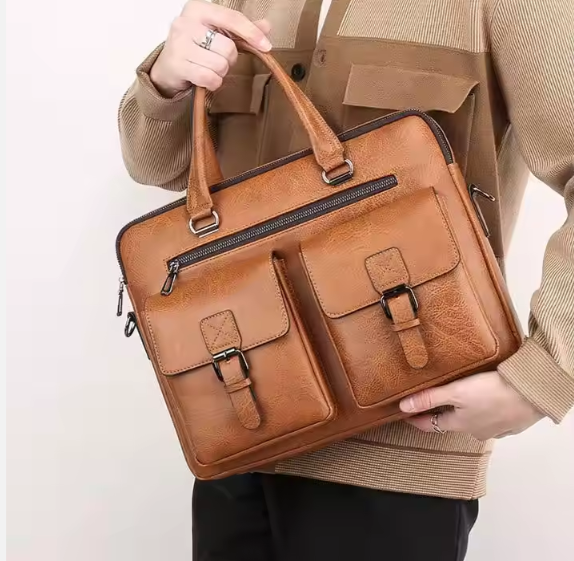 Brown leather briefcase held by a person wearing a beige jacket.