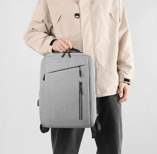 Person holding a gray "nylone bag pack" against a plain background